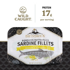 Brunswick Sardines served on crackers with dill, ideal snack.