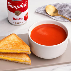 Campbell's Tomato Soup pack of four cans on a pantry shelf.