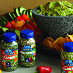 Hand pouring Litehouse herb blend into ripe avocados for quick guac prep.