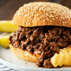 Pouring McCormick Sloppy Joes Seasoning Mix into a sizzling beef pan.