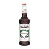 Monin Blackcurrant Syrup bottle on a bar enhances beverages.