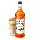 Monin Hazelnut Syrup 1L bottle enhances beverages with caramelized hazelnut flavor.