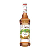Monin Praline Syrup bottle pouring into a latte with rich praline aroma.