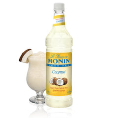Monin Sugar Free Coconut Syrup bottle being poured for a tropical drink