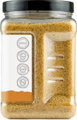 Spoon dispensing Nutricost demerara sugar for measured sweetening.