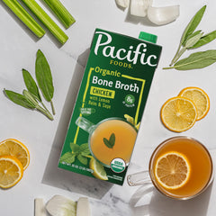 Pacific Foods organic broth with lemon balm and sage beside fresh lemon slices