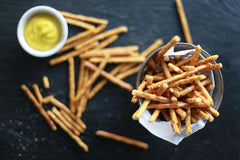 Three-pack pretzels sticks in reusable packaging for easy snacking.