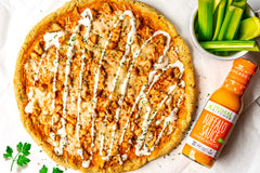 Primal Kitchen Buffalo Sauce wings-dipping scene, tangy medium heat.