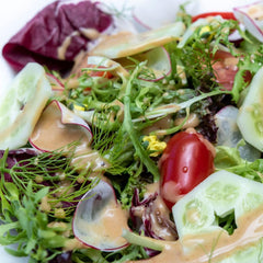 Red Shell Miso Dressing pouring from glass bottle into a bowl.