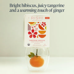Warm cup with steam showing vibrant hibiscus and tangerine flavors.
