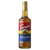Torani Hazelnut Syrup bottle pour showcases rich nutty flavor for coffee and desserts.