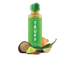 TRUFF jalapeño lime black truffle hot sauce being poured over tacos.