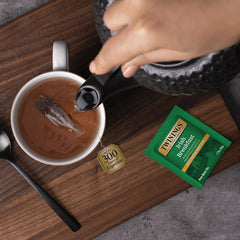 Pouring hot water over a Twinings tea bag into a cup for brewing.