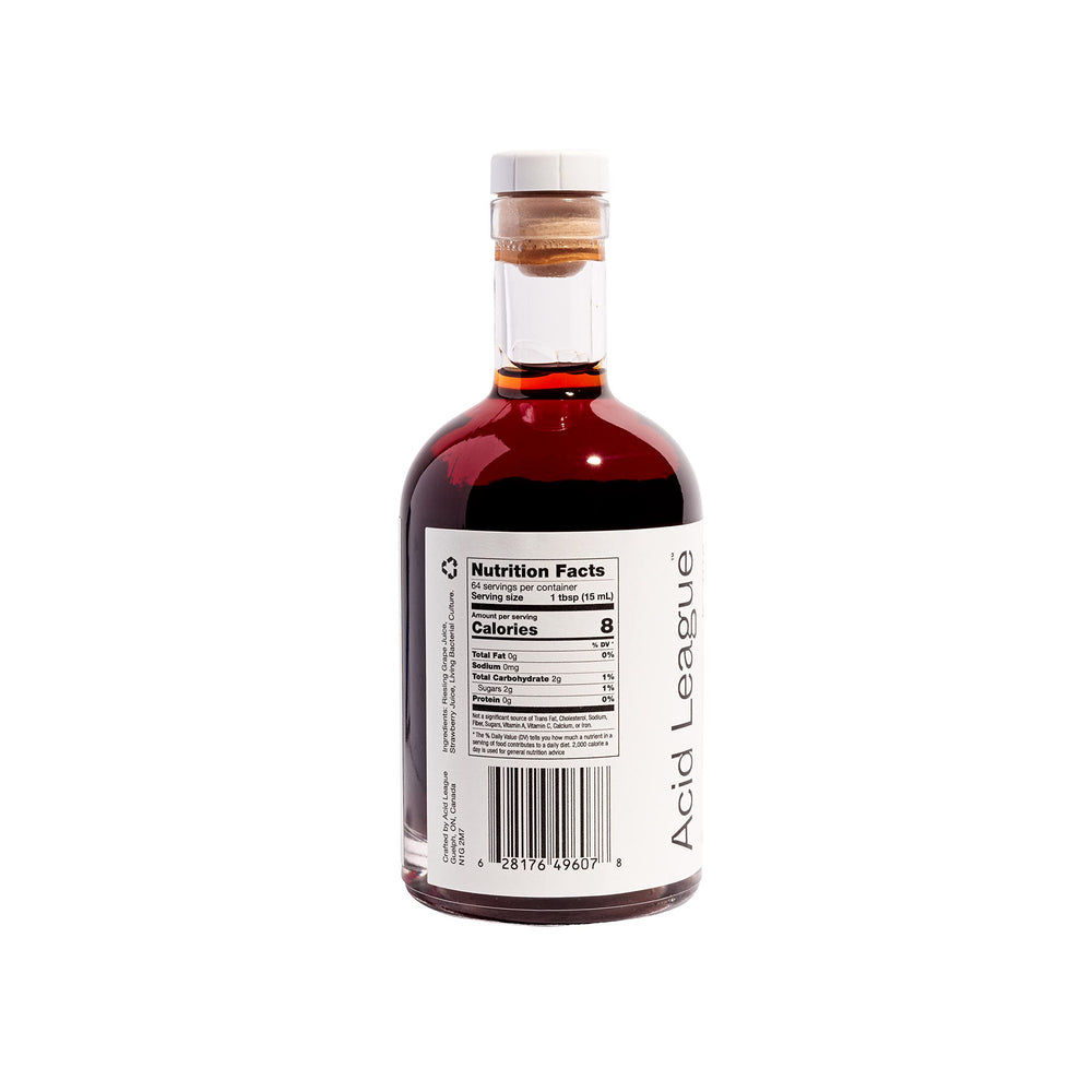 Pouring Acid League Strawberry Rosé Living Vinegar to brighten a salad.