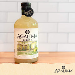 Pouring Agalima Margarita Mix over ice for bar-quality cocktails at home.