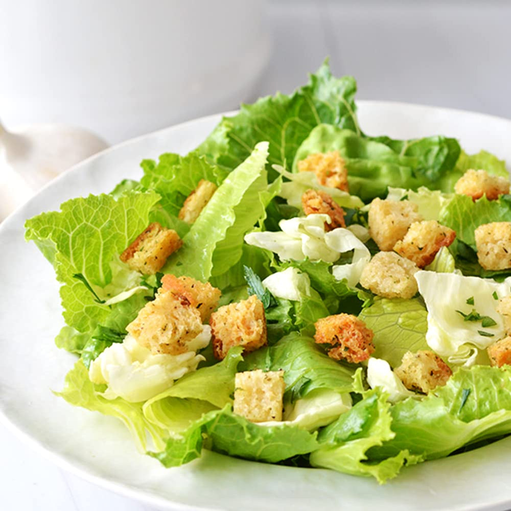 Aleia’s Garlic Croutons sprinkled on salad bowl for crunch