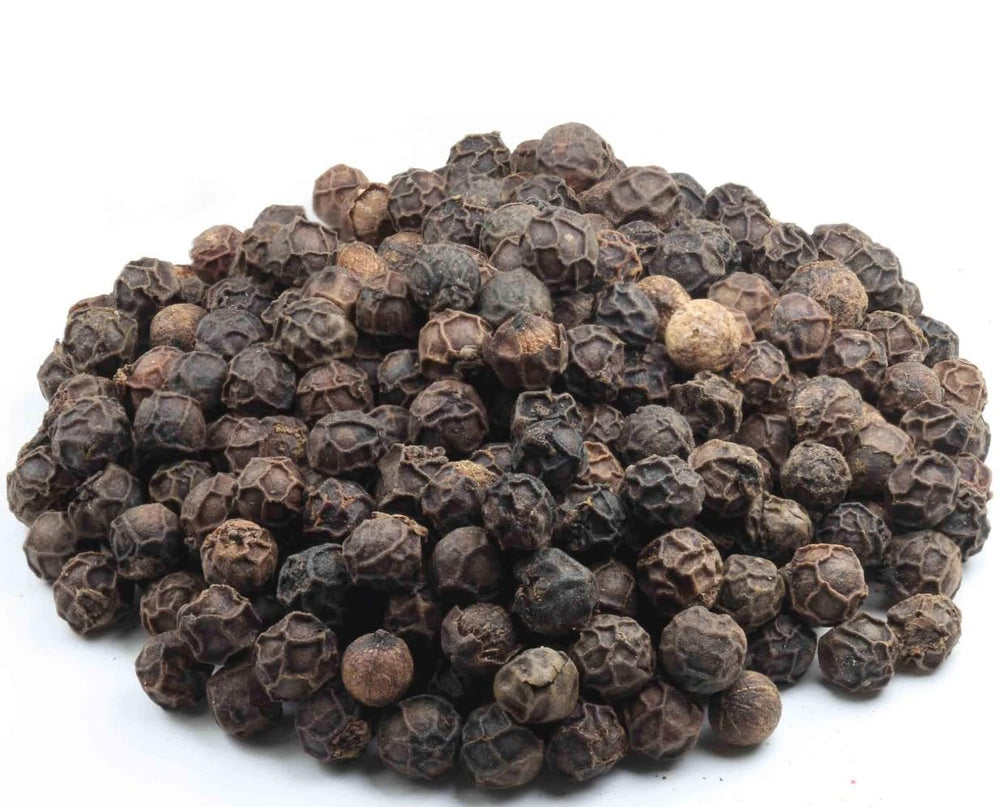 Whole Tellicherry peppercorns pour from Amazon Grocery bag over dishes.