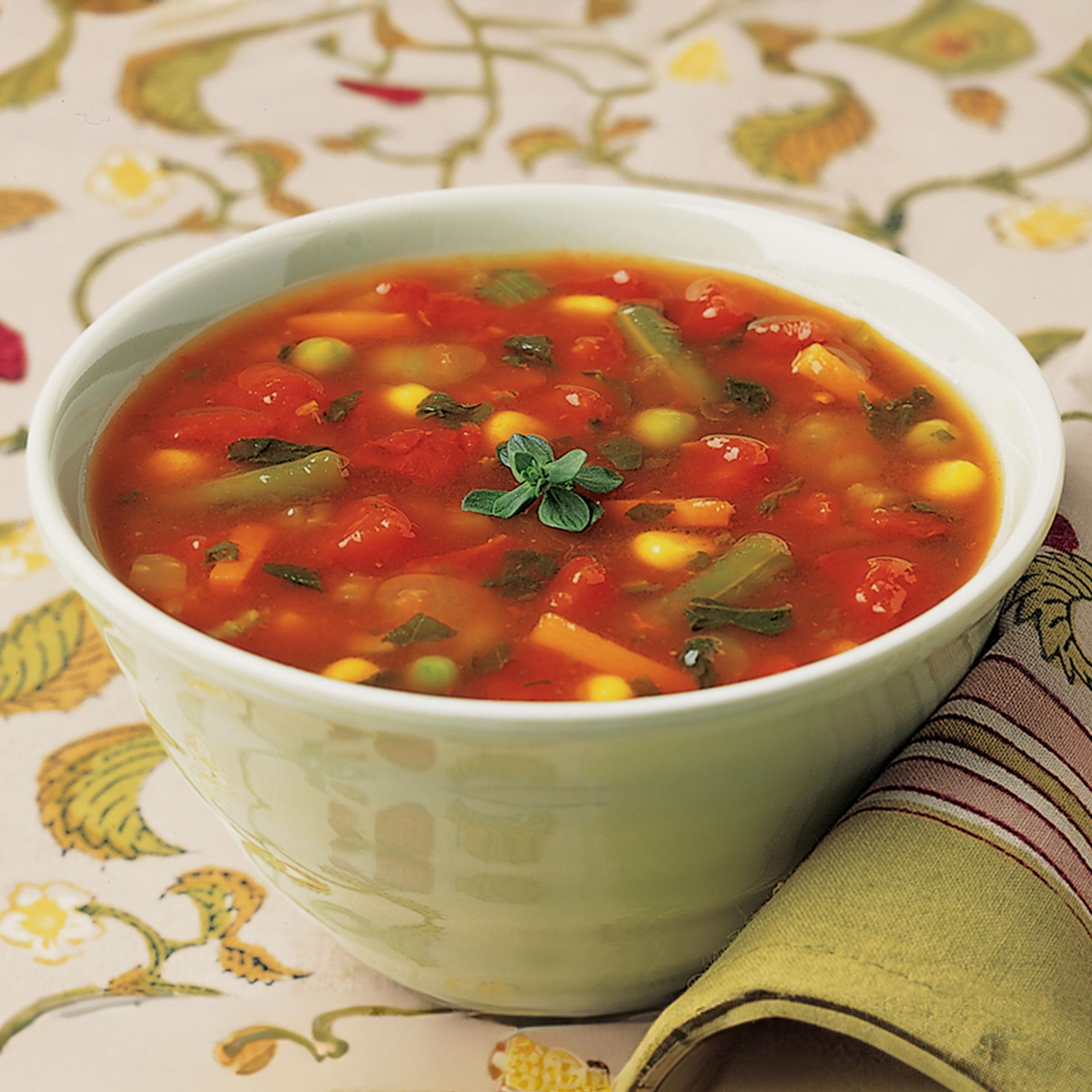 Serving bowl with warm soup showing chunky vegetables and tomato broth.