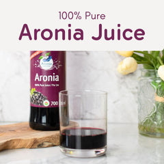 Aronia Original juice in a clear glass, bold ruby hue.