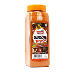 Badia Sazón Tropical bottle pouring over poultry for vibrant flavor and color.