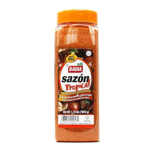 Pouring Badia Sazón Tropical to season grilled meats with golden hue.
