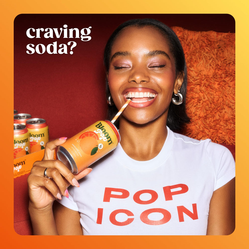 Hand reaches for Bloom Pop Orange can, caffeine-free refreshment for any time.