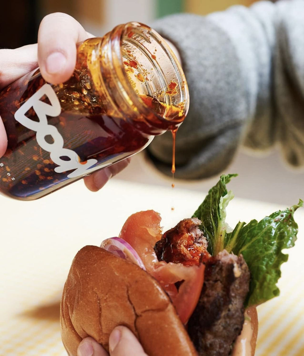Boon Sauce Chili Oil bottle beside a sizzling skillet for ready-to-use heat.