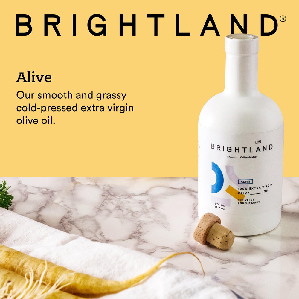 Brightland Alive olive oil being poured over greens.