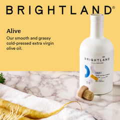Brightland Alive olive oil being poured over greens.