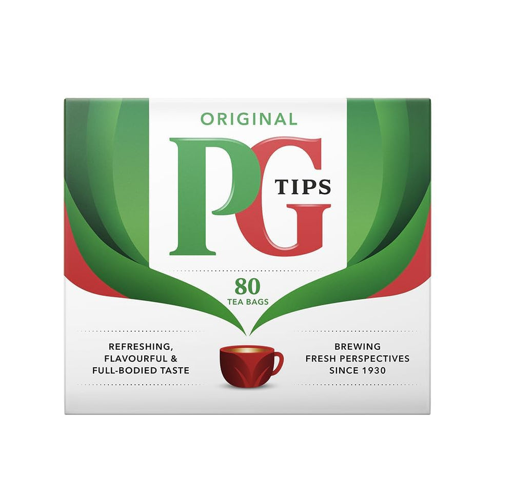 PG Tips tea bags in a mug beside a splash of milk.