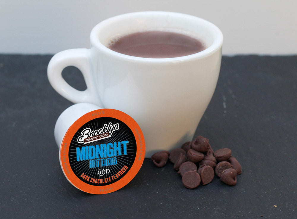 Brooklyn Beans Midnight Cocoa pods cup with steam, conveying cozy indulgence.
