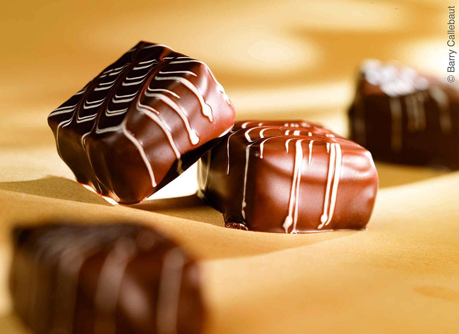 Melted chocolate drips onto glossy dessert surface.