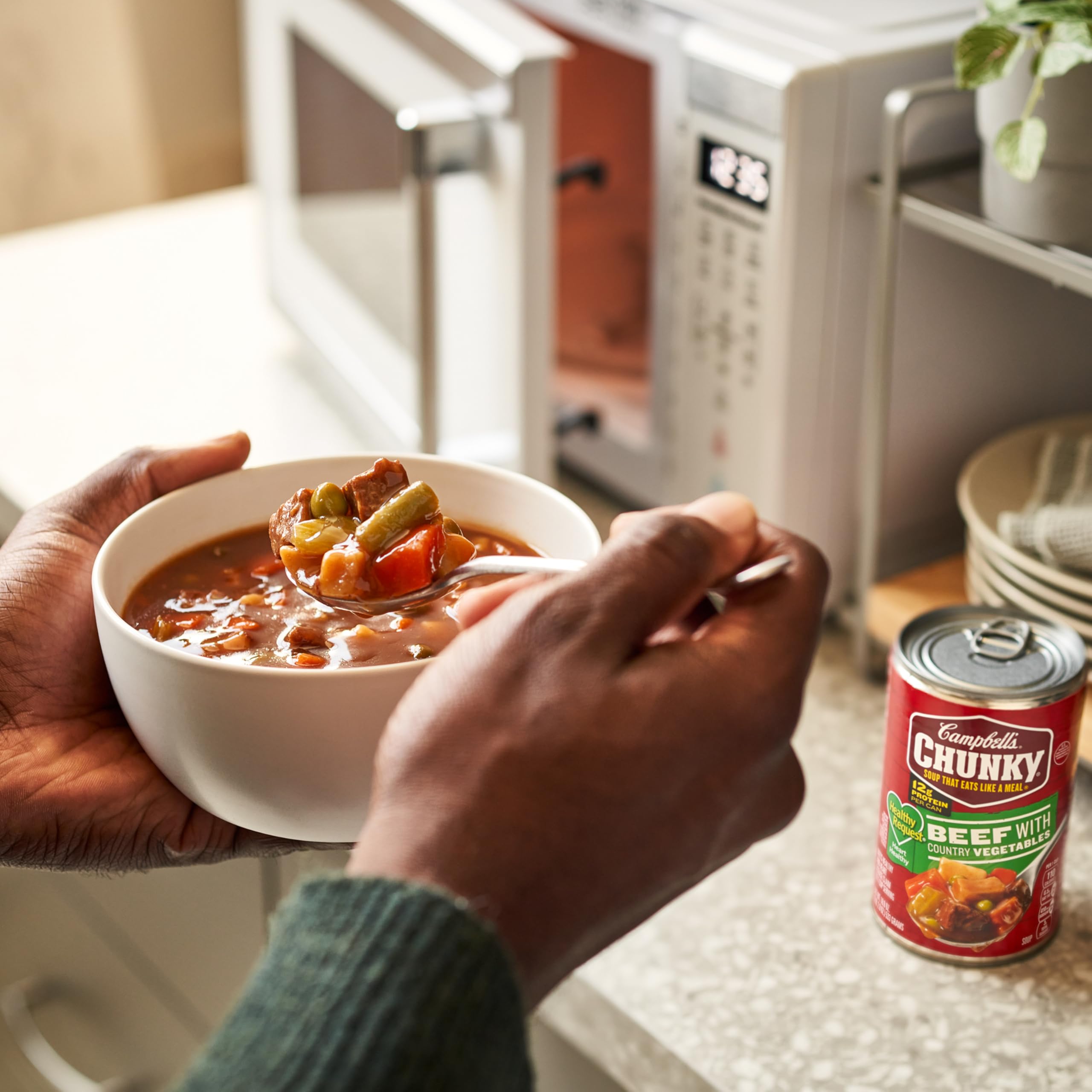 Campbell's Chunky Beef Soup warming by campfire for outdoor comfort.