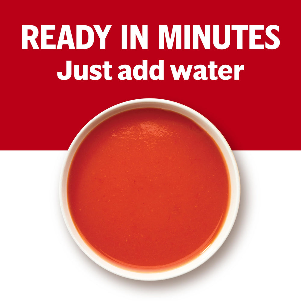 Pouring Campbell's tomato soup into a bowl, steam rising.