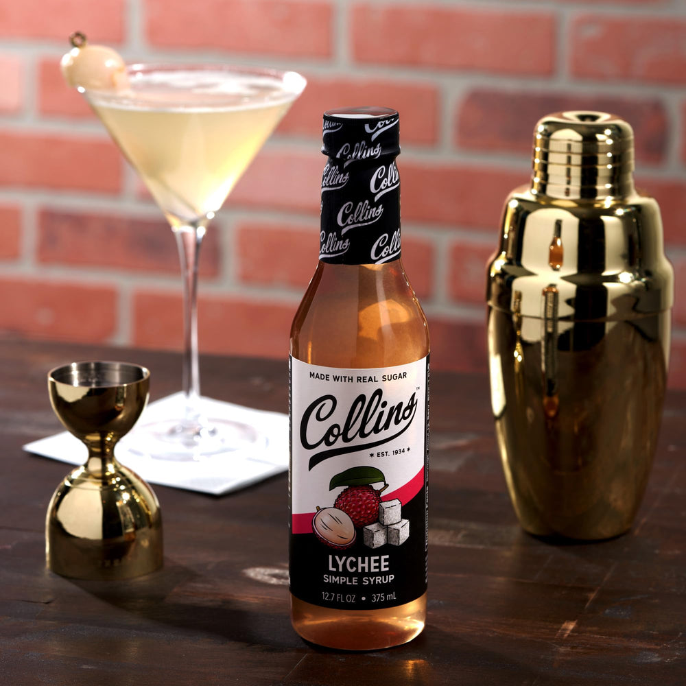 Collins Lychee Syrup beside mojito ingredients for a party-ready mix