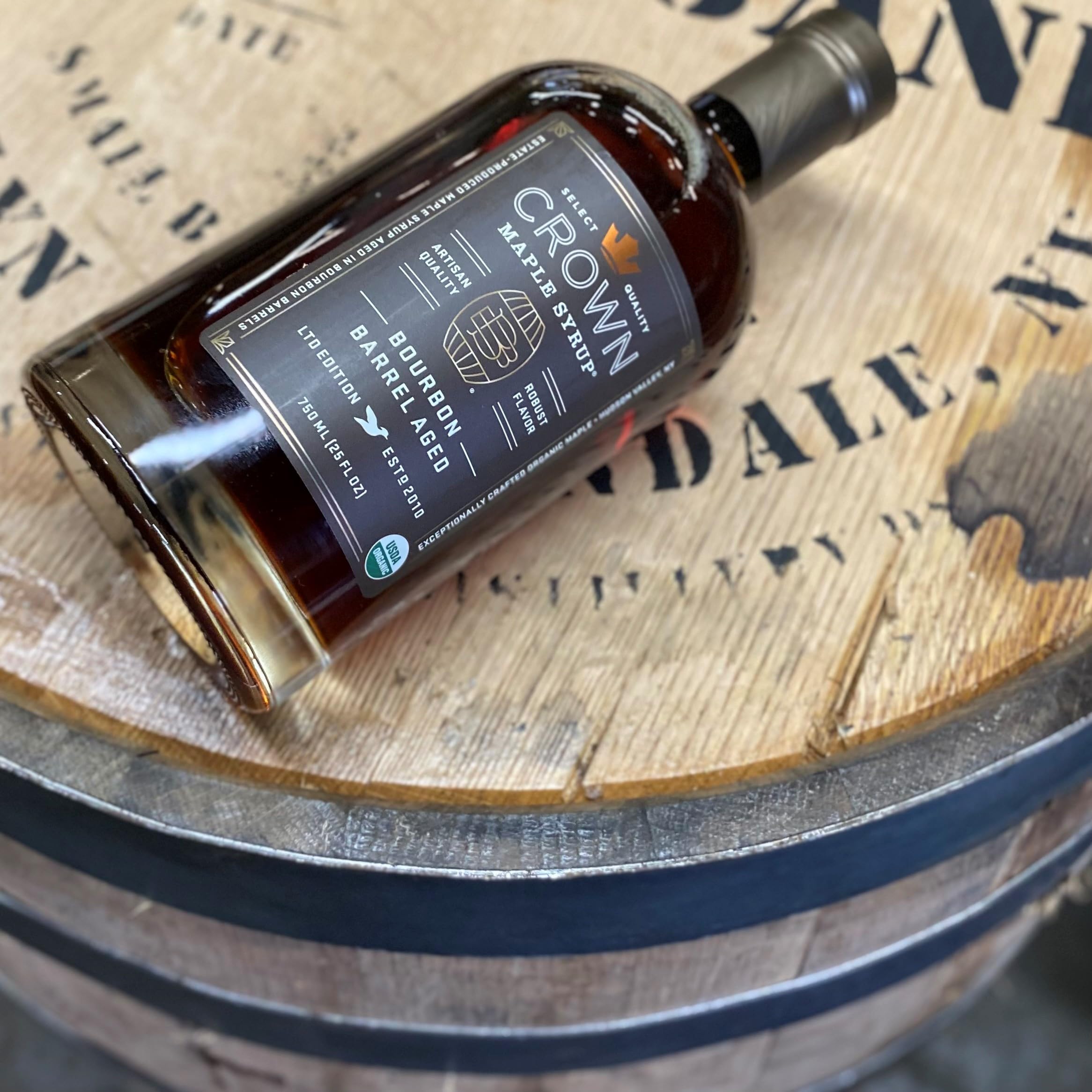 Crown Maple syrup beside a wooden board, versatile for marinades and sauces.