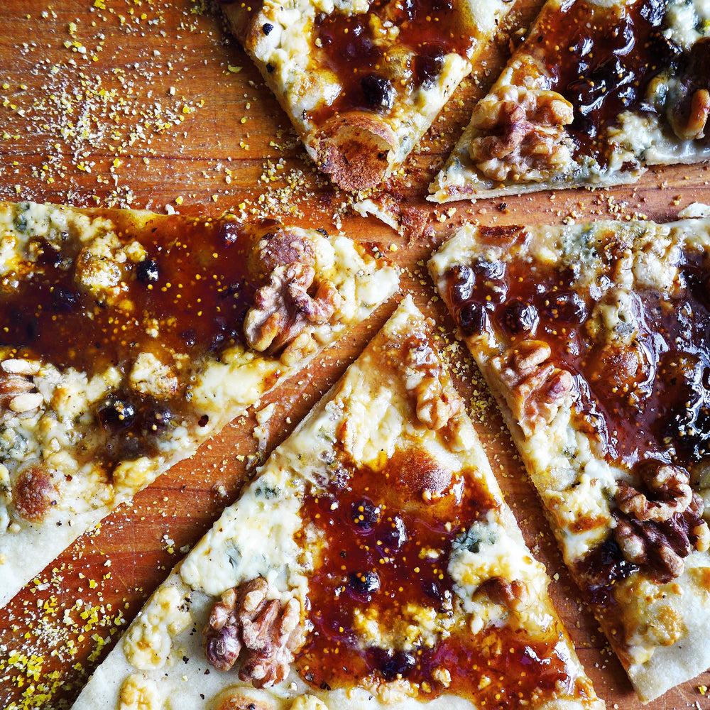 Divina fig spread atop pizza with arugula and prosciutto for flavorful bites.