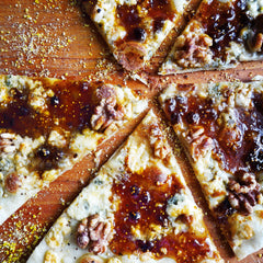 Divina fig spread atop pizza with arugula and prosciutto for flavorful bites.