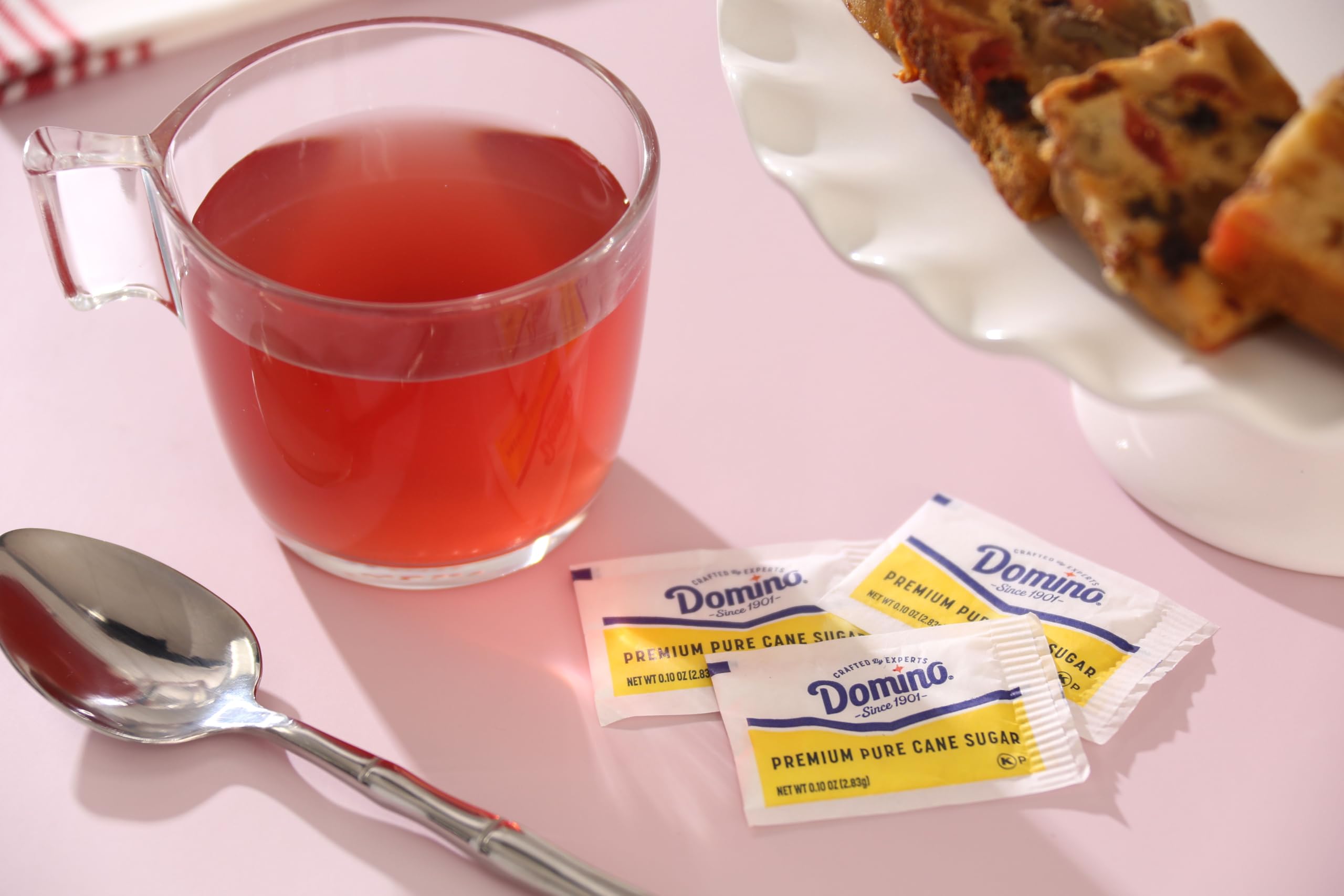 Domino sugar packets on a countertop with a coffee cup for daily use.