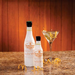 Two bottles of Fee Brothers West Indian Orange Bitters on a bar setup for cocktails