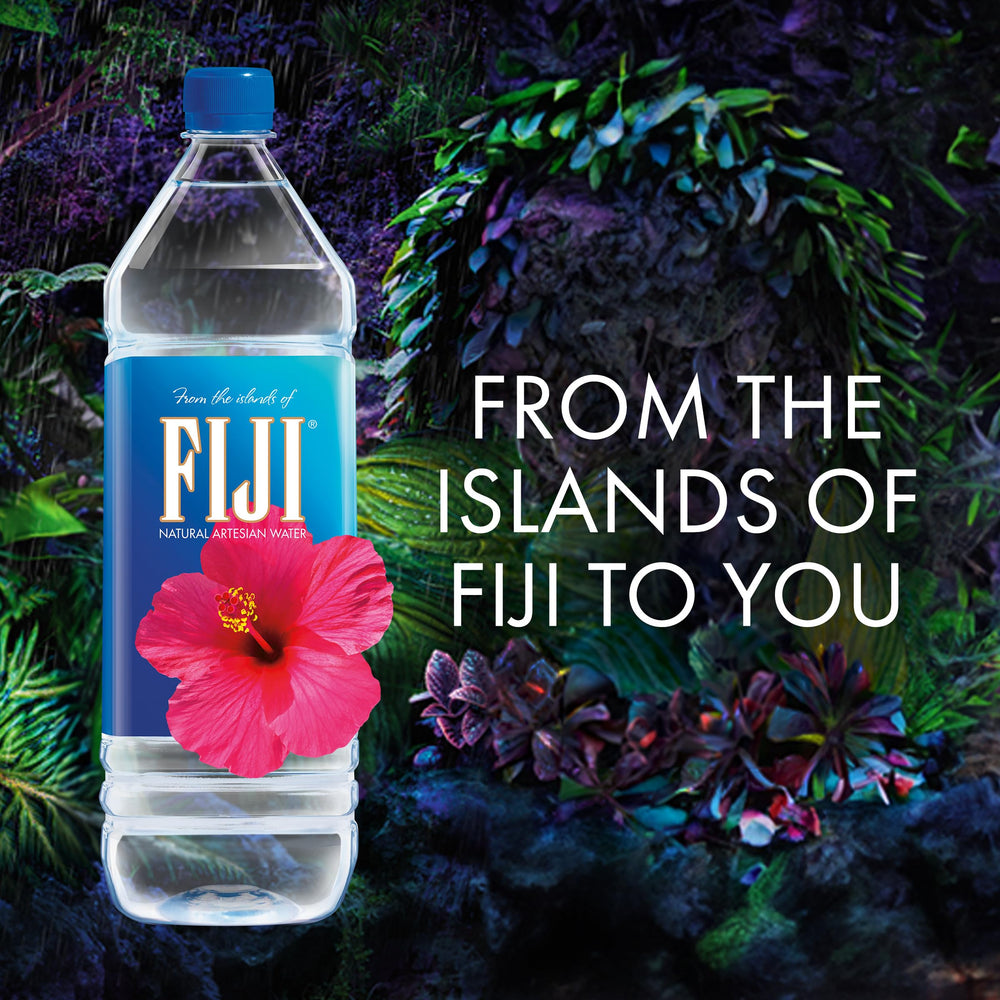 FIJI Water on a desk beside a laptop for everyday hydration at work.