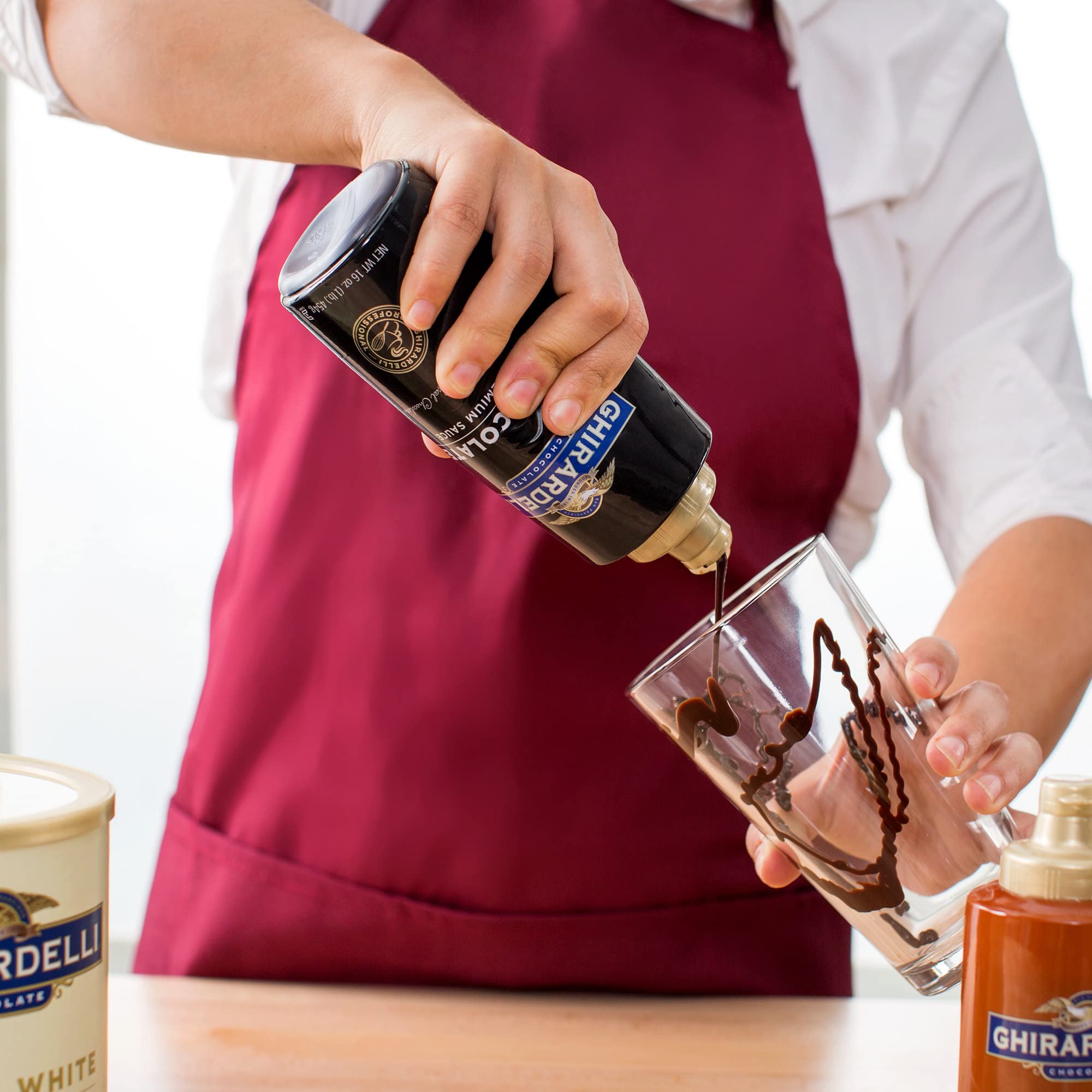 Ghirardelli chocolate sauce being added to hot chocolate for indulgent finish.