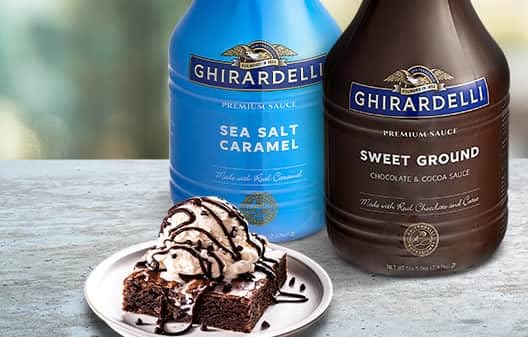 Ghirardelli Sea Salt Caramel bottle beside baking setup signals premium topping.