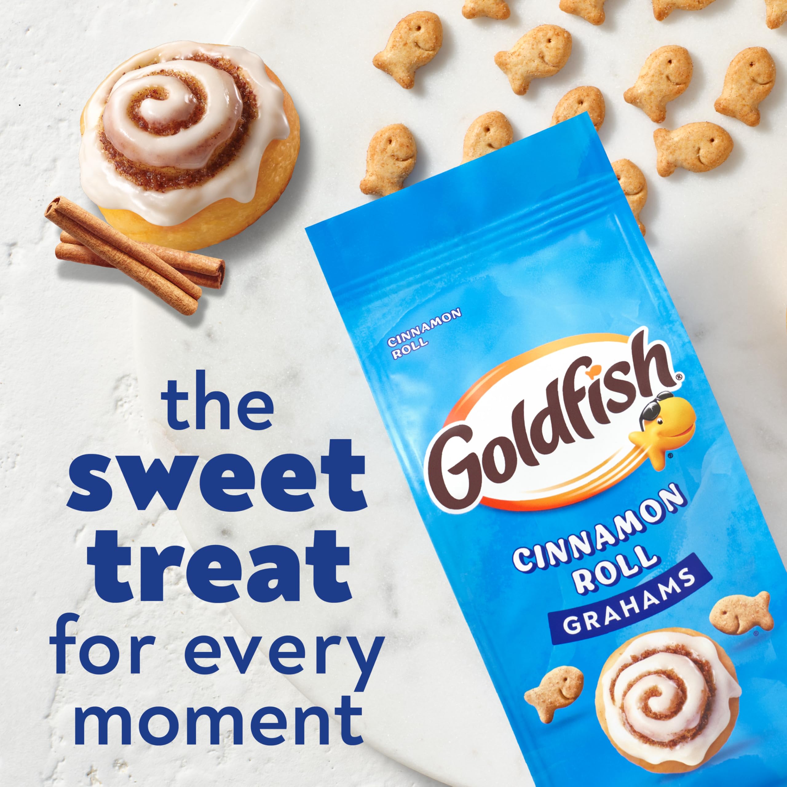 Goldfish Grahams Cinnamon Roll crackers held in hands, convenient for on-the-go bites.