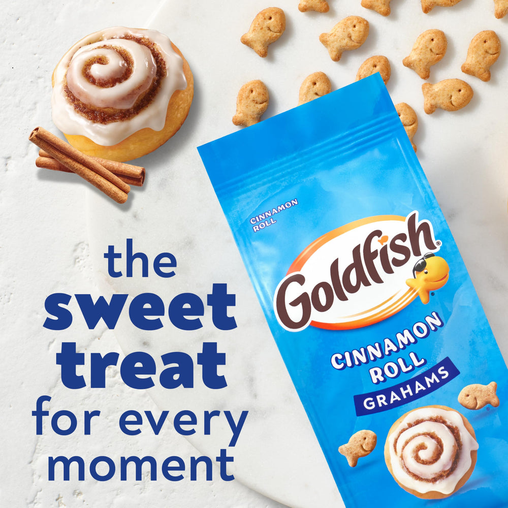 Goldfish Grahams Cinnamon Roll crackers held in hands, convenient for on-the-go bites.