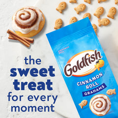 Goldfish Grahams Cinnamon Roll crackers held in hands, convenient for on-the-go bites.