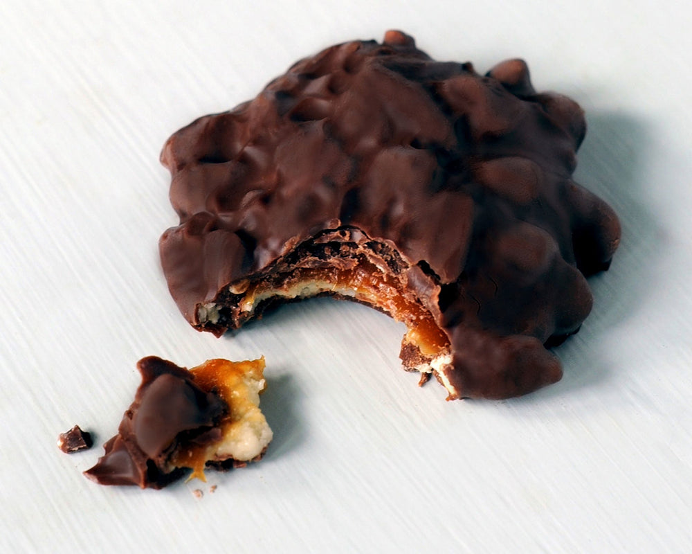 Mouthwatering bite of GooGoo Clusters Original with creamy milk chocolate and chewy centers.