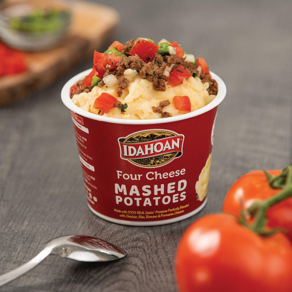 Idahoan Four Cheese Cups on a kitchen counter with ingredients nearby.