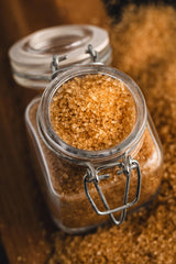 Coarse crystals of India Tree Demerara sugar resting on a saucer beside tea