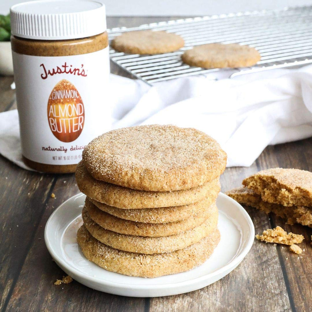 Justin's Almond Butter Cinnamon beside almonds highlights wholesome ingredients.